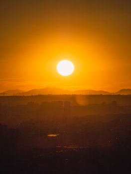 A mesmerizing view of the sun setting over Madrid's cityscape, casting a golden glow.