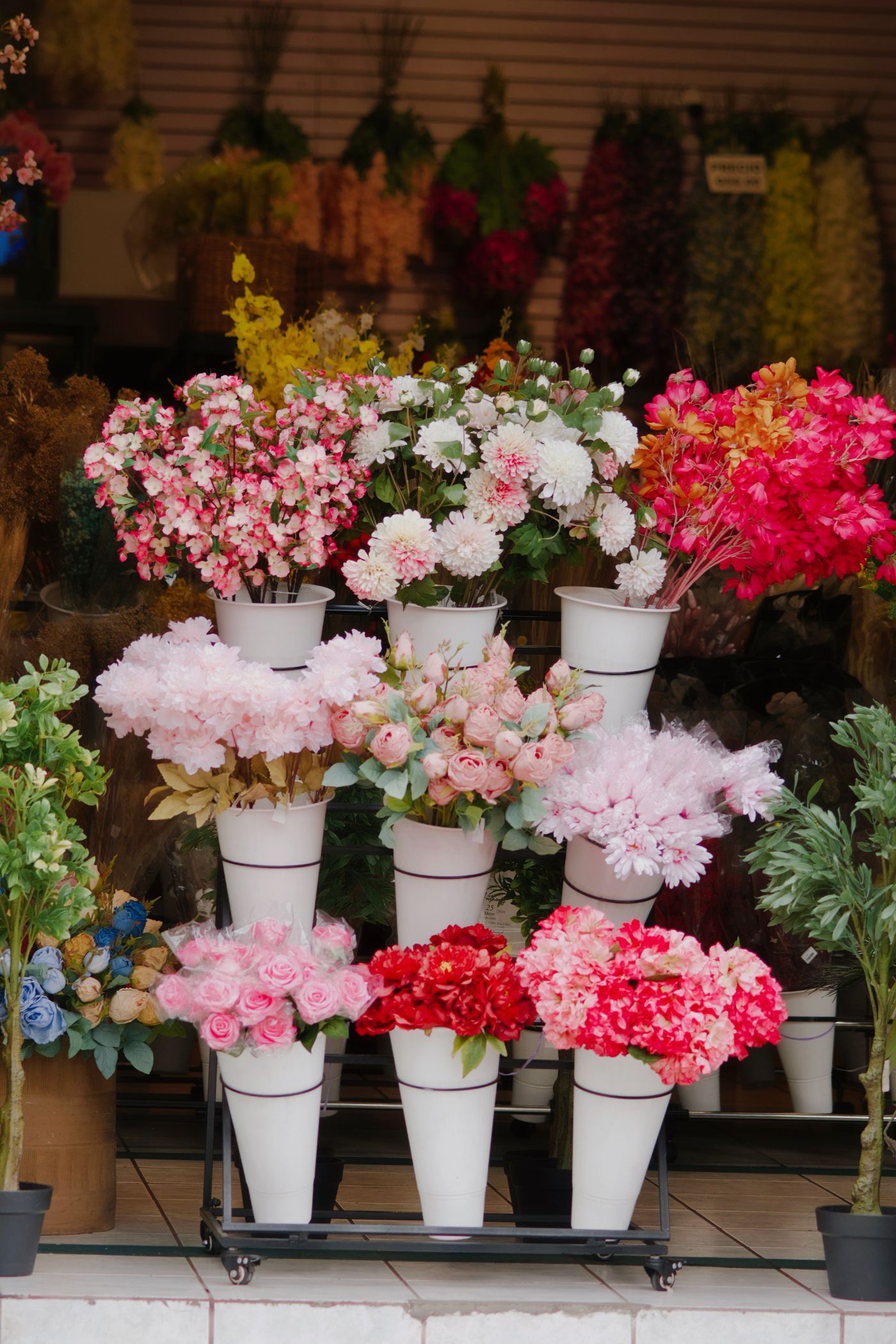 Bunte frische Blumen in Eimern vor einem Blumenladen
