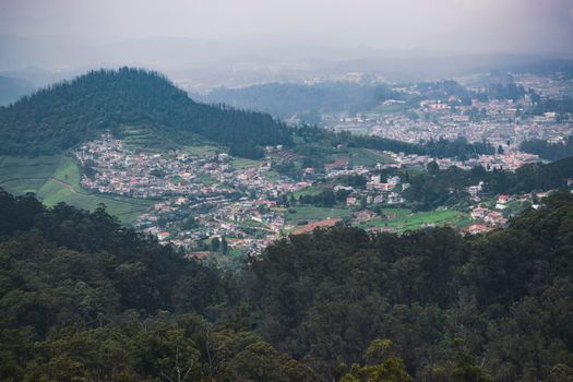 Aerial view of lush Ooty hills and townscape surrounded by verdant forests.