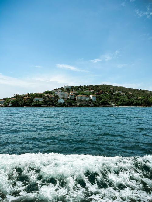 Free Idyllic coastal town landscape with lush hills and sea waves creating a calming atmosphere. Stock Photo