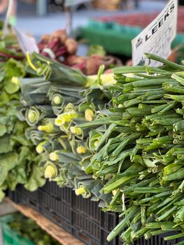 Vibrant display of fresh leeks and greens at an outdoor farmer's market stand.. vibrant, display, fresh