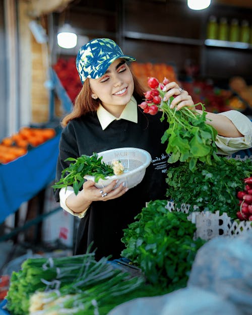 A woman in a black shirt is holding a bowl of vegetables
