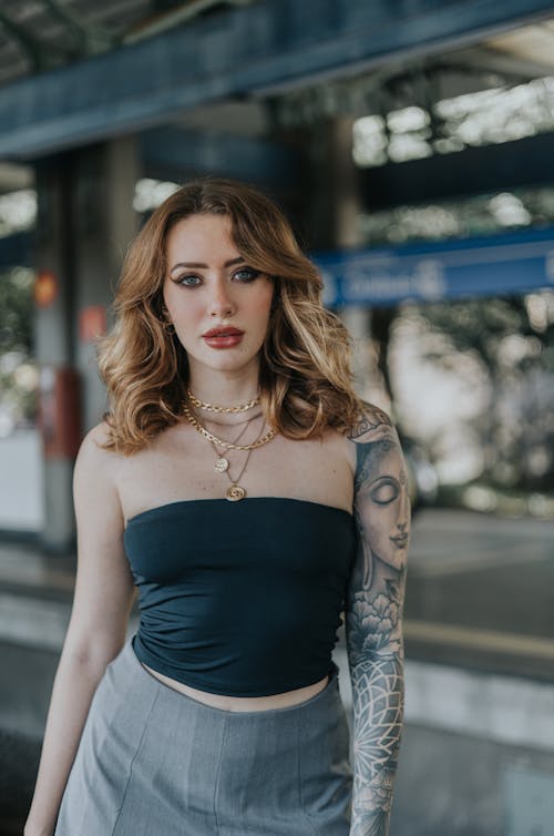 A woman with tattoos standing in front of a train station