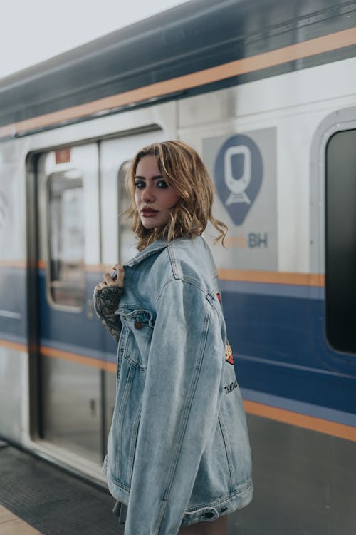 A woman in a denim jacket standing next to a train