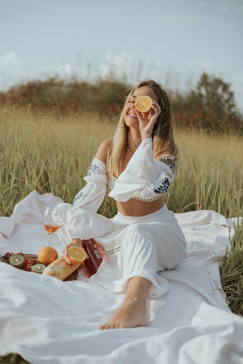 A woman sitting on a blanket eating fruit