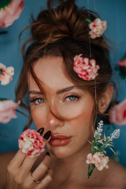 A woman with flowers in her hair and a flower on her nose