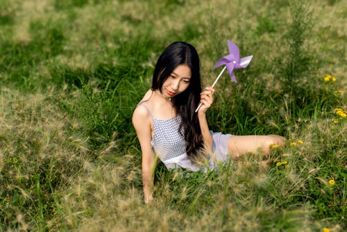 A woman sitting in a field with a purple pinwheel