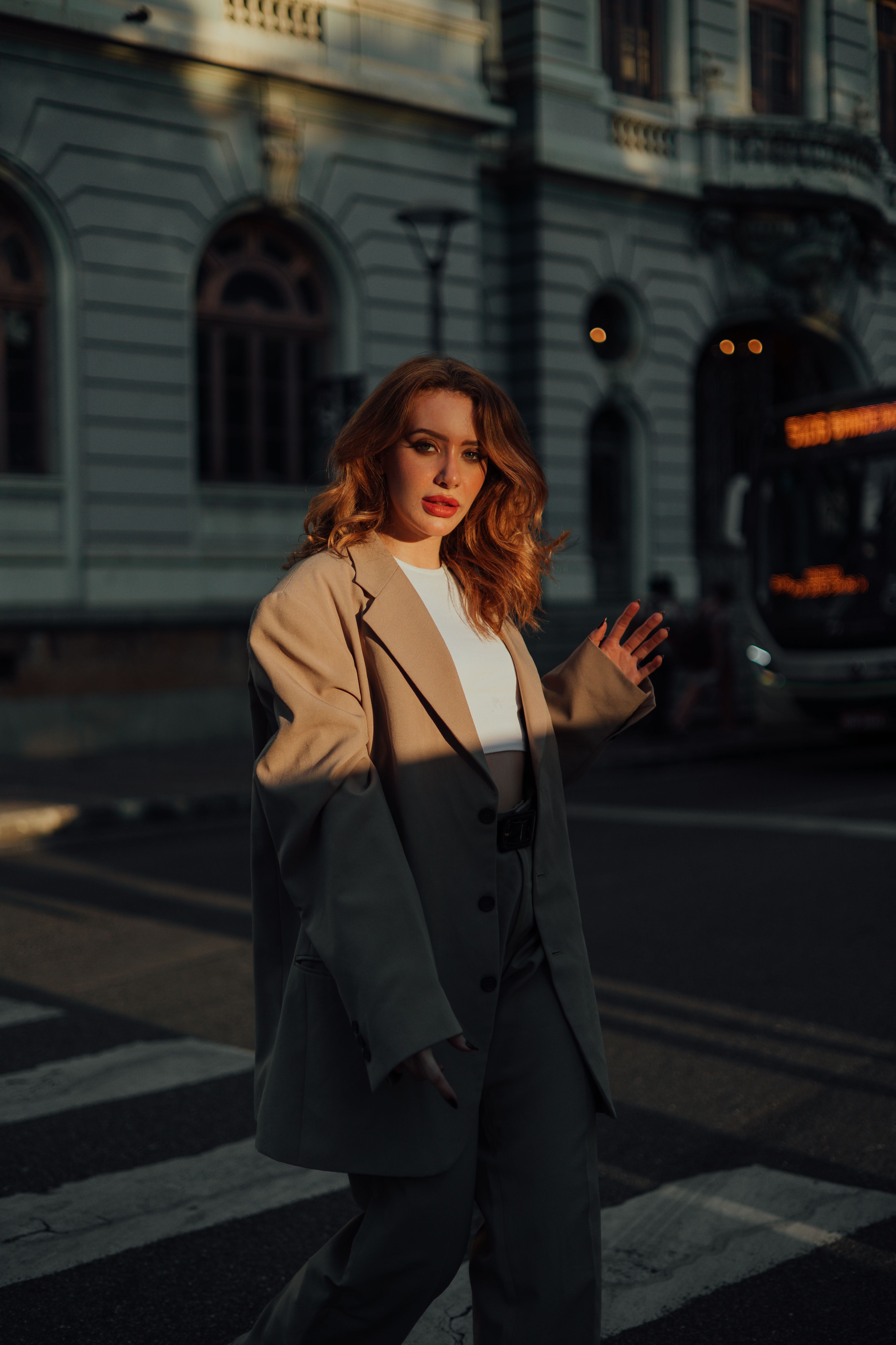 Woman in a tailored coat crossing a city street at golden hour, photo by Wesley Davi on Pexels