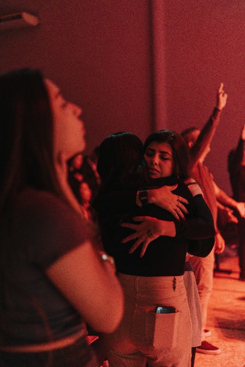 Free Two women embrace passionately in a dimly lit nightclub, red lights casting a warm mood. Stock Photo