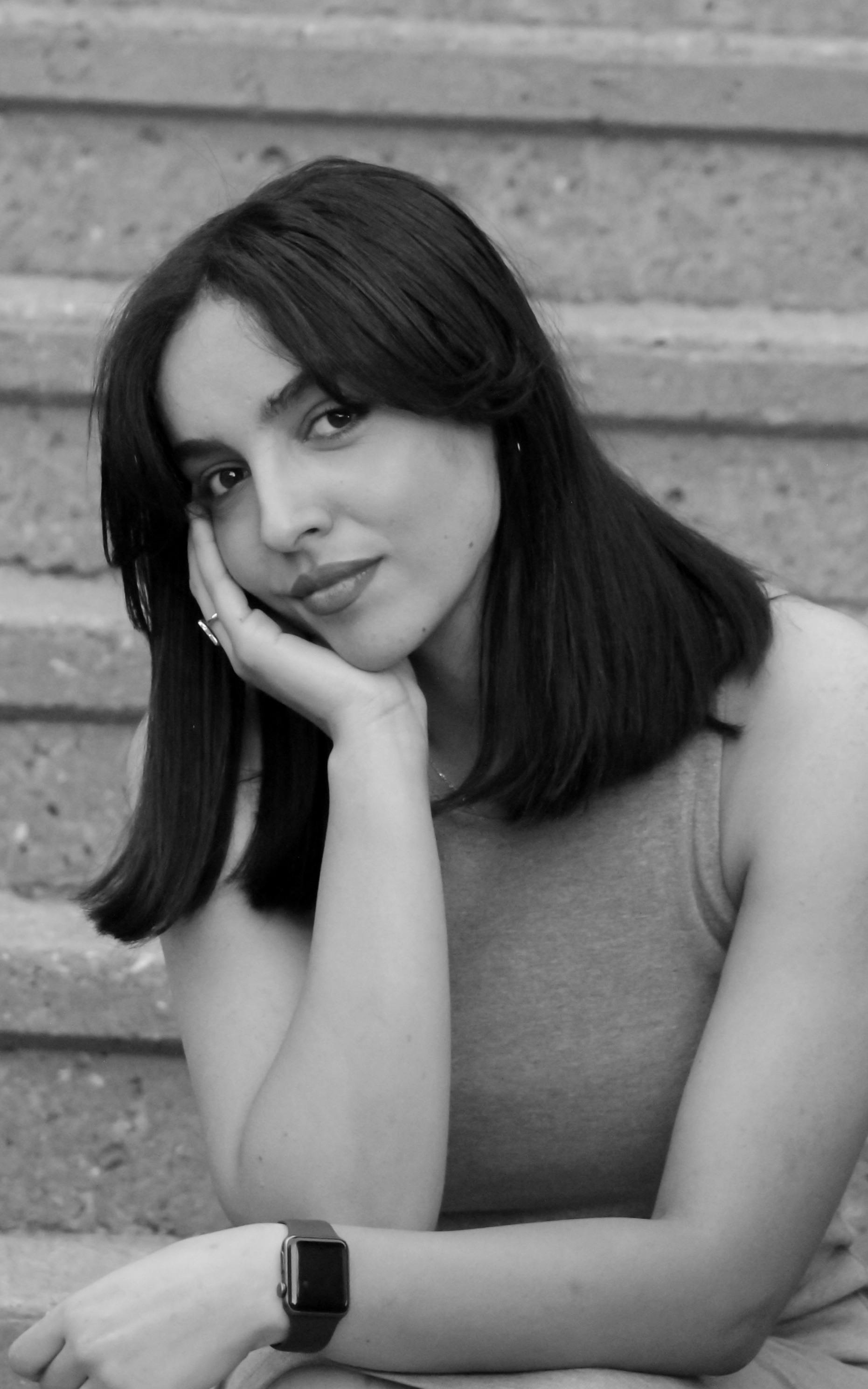 A stunning black and white portrait of a brunette woman sitting gracefully.