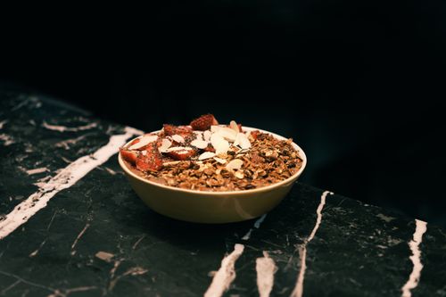 Free Close-up of a nutritious granola bowl with strawberries and almonds on a marble surface. Stock Photo
