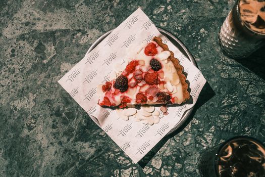 Top view of a delicious berry tart slice with cream on a plate, perfect for a dessert treat.