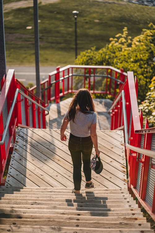 A woman walking up stairs with a red railing