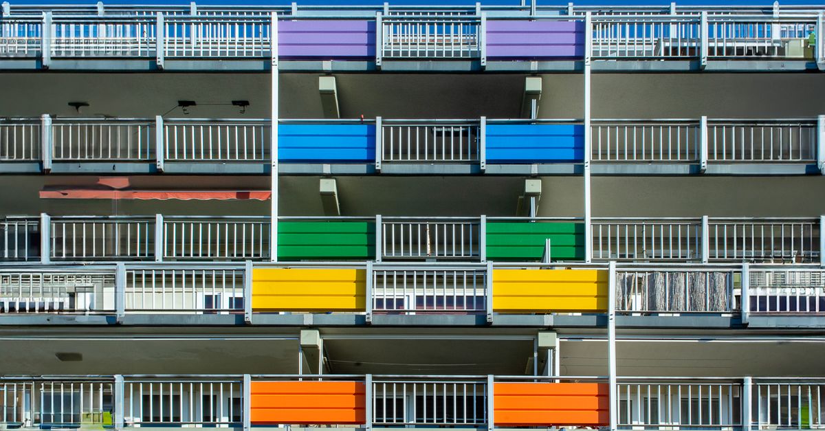 Vibrant apartment building with multi-colored balconies under a clear blue sky.