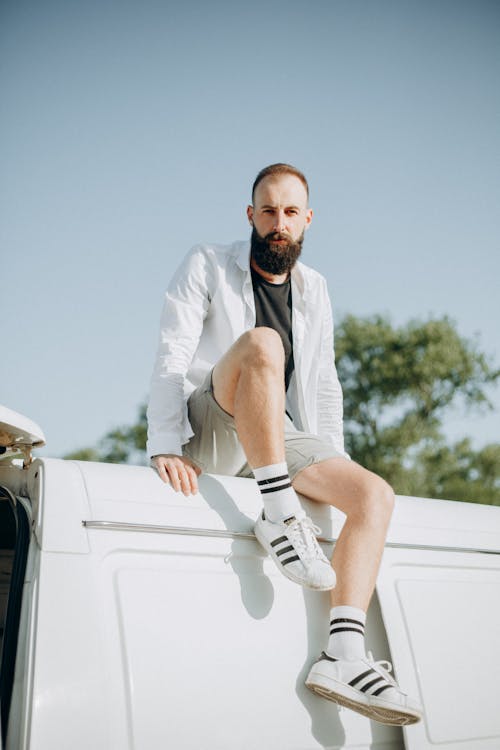 Foto De Un Hombre Con Camisa Blanca De Manga Larga Sentado En Un Panel Blanco