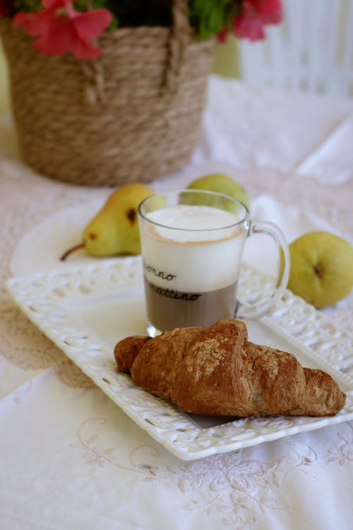 A croissant and coffee are on a plate