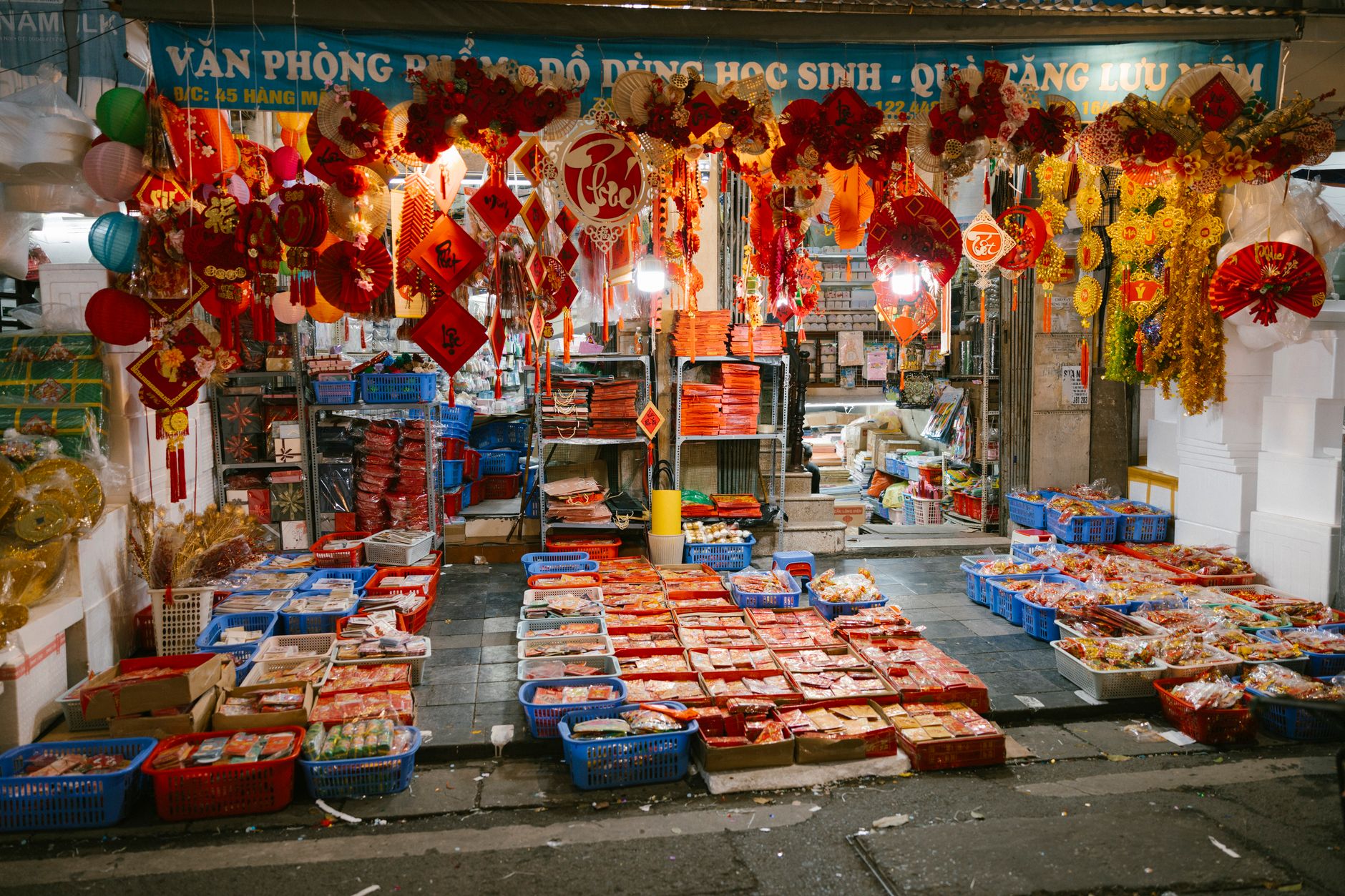 Vibrant display of traditional decorations and merchandise at an Asian market stall during night time.