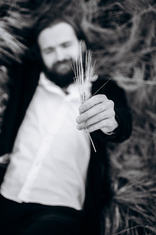 Shallow Focus Photography of a Man Holding Dried Grass