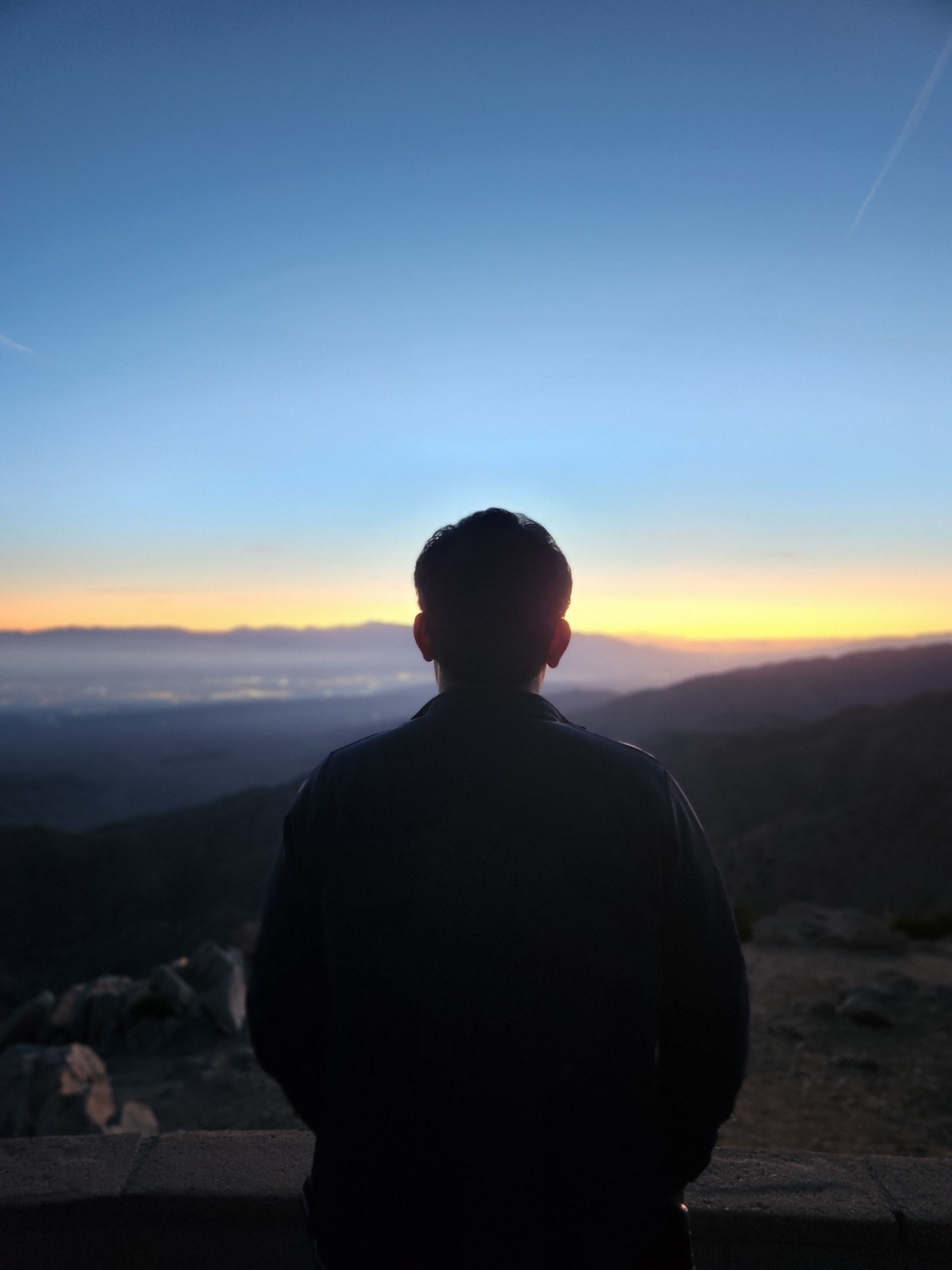 Silhouette of a person overlooking mountains at sunset in Joshua Tree, California.