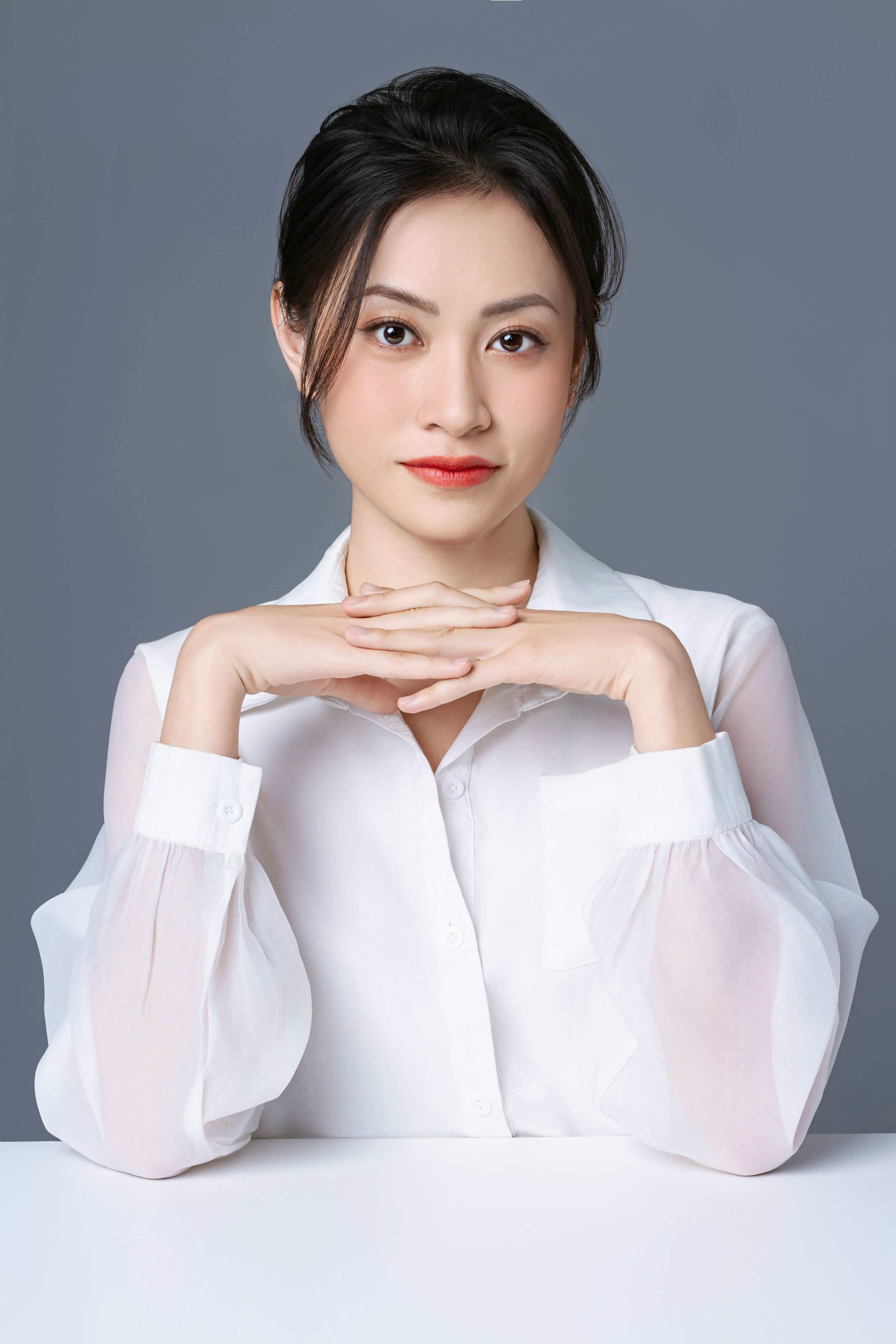 Elegant professional portrait of an Asian woman in a formal white shirt, exuding confidence and poise.