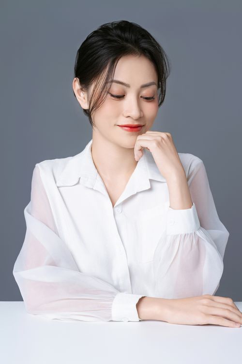 Free Stylish studio portrait of a young woman in an elegant white blouse, exuding confidence and grace. Stock Photo