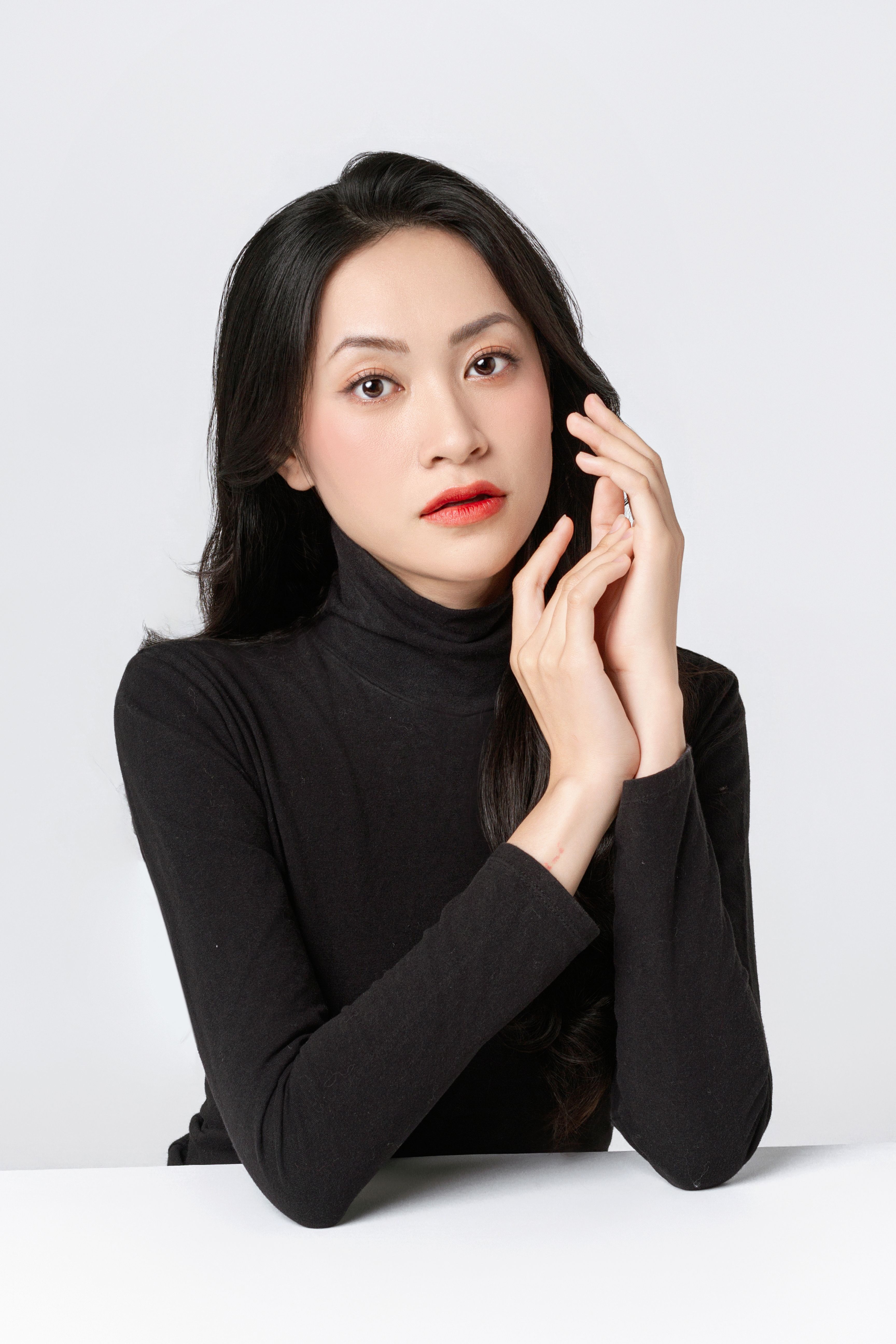 Stylish studio portrait of an Asian woman in a black turtleneck, exuding elegance and sophistication.