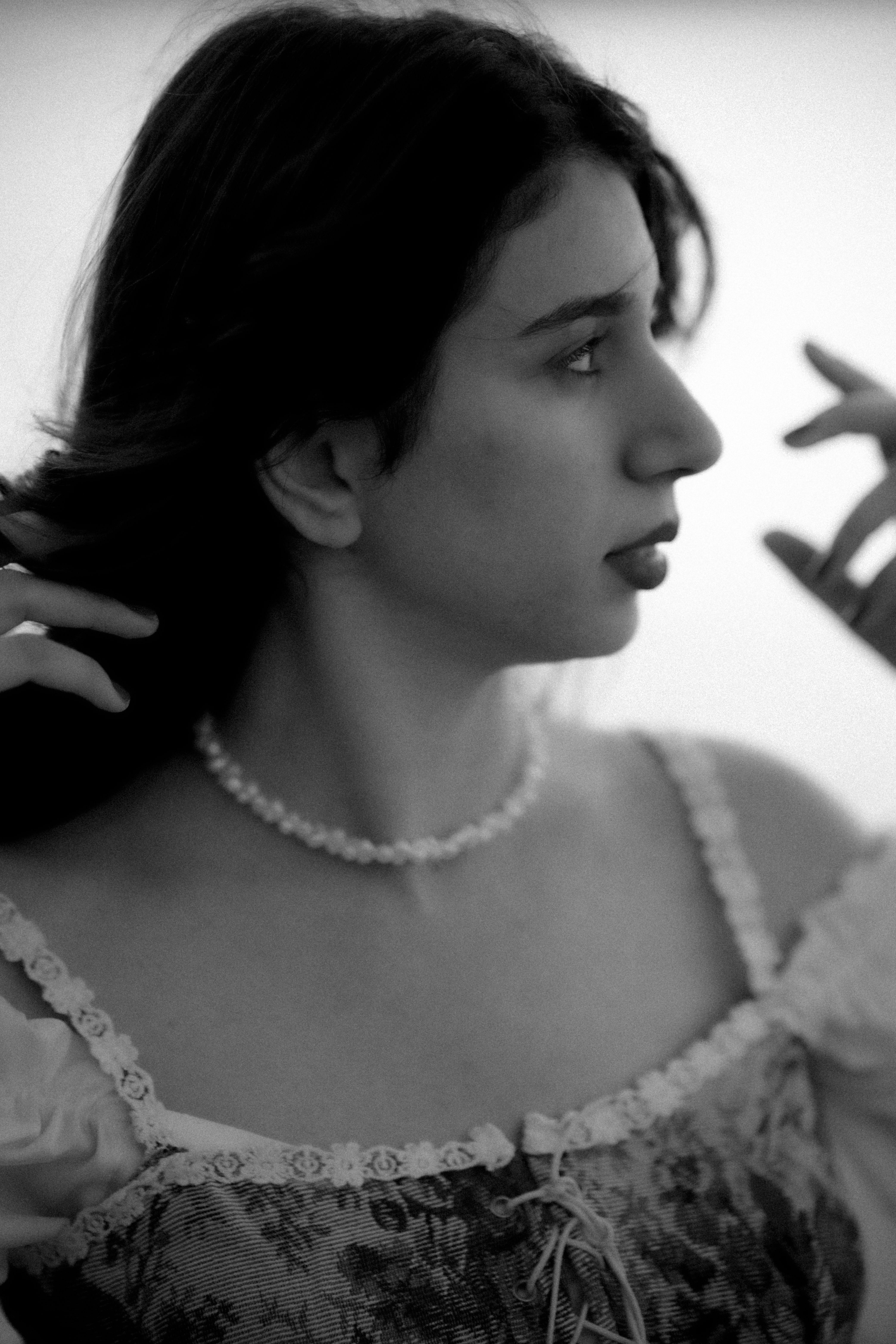 Stunning black and white portrait of a woman in a corset and necklace, looking serene.