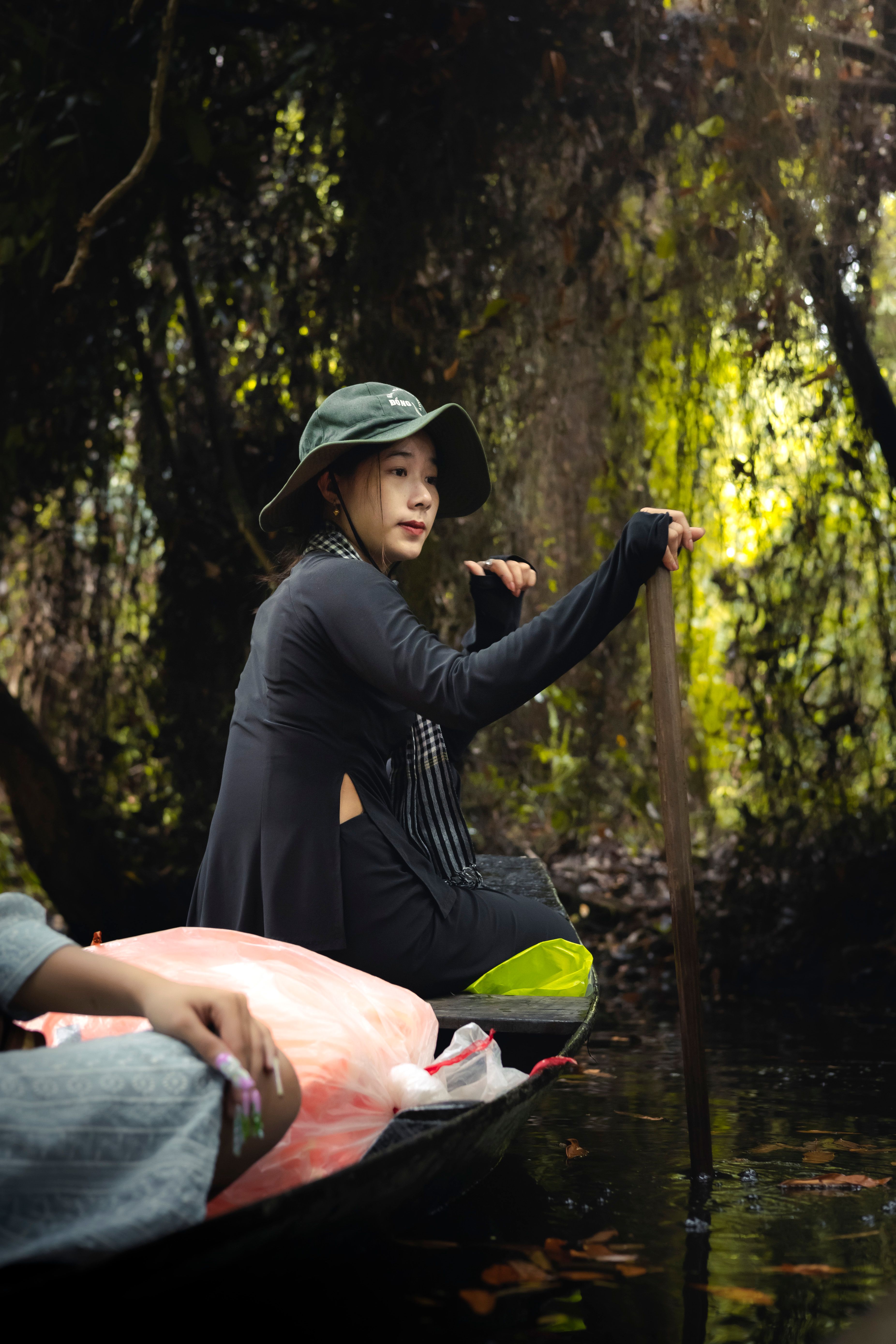 Asian woman paddling a canoe through lush, verdant waters in Sa Đéc, Vietnam, surrounded by nature's beauty.