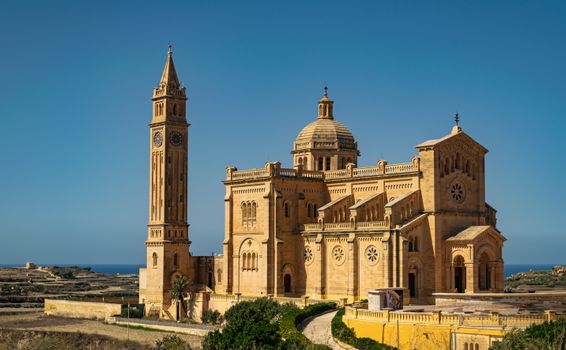 Scenic view of Ta' Pinu Basilica in Għarb, Malta, framed against a vibrant clear sky.