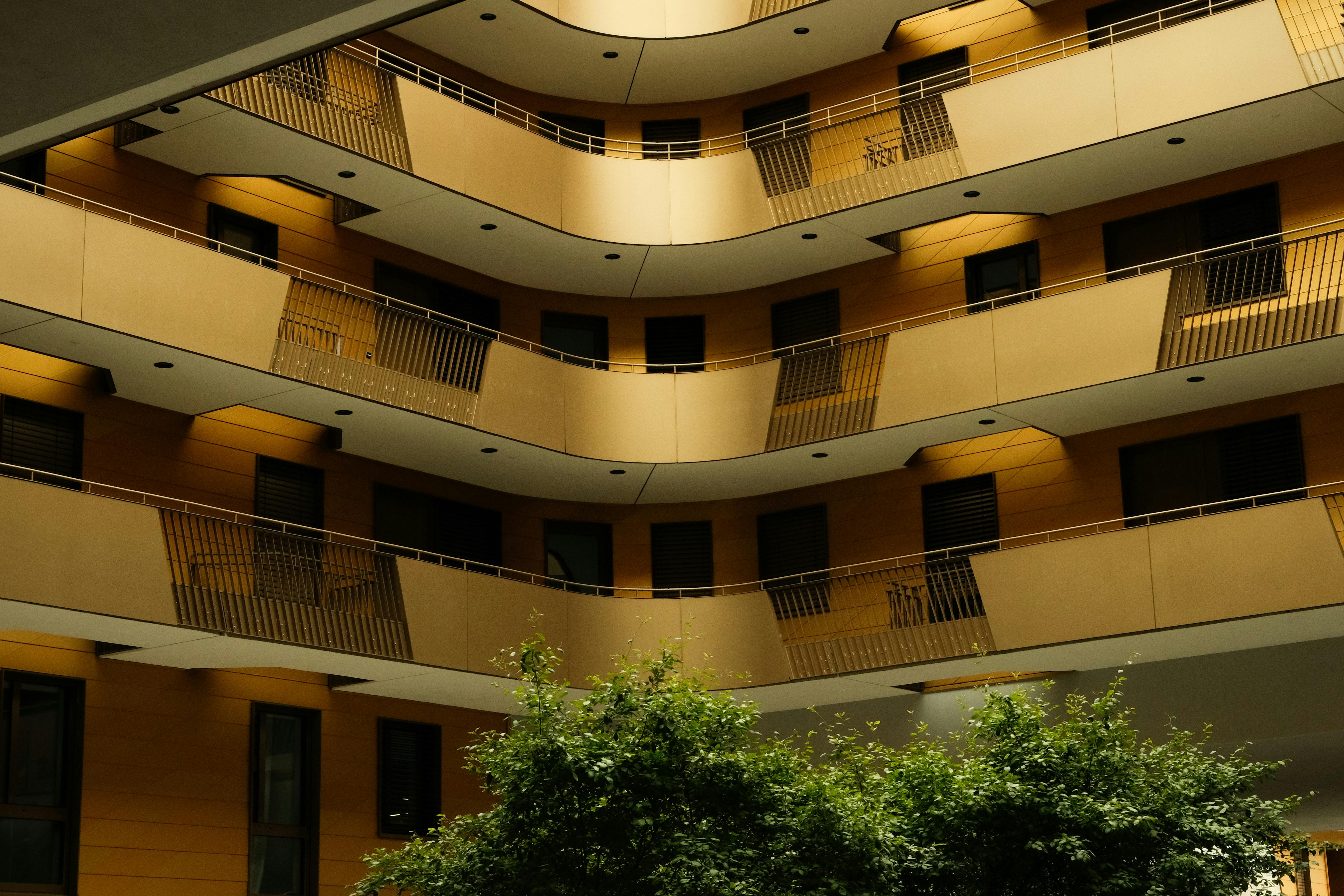 Contemporary residential building with multiple balconies and lush greenery.