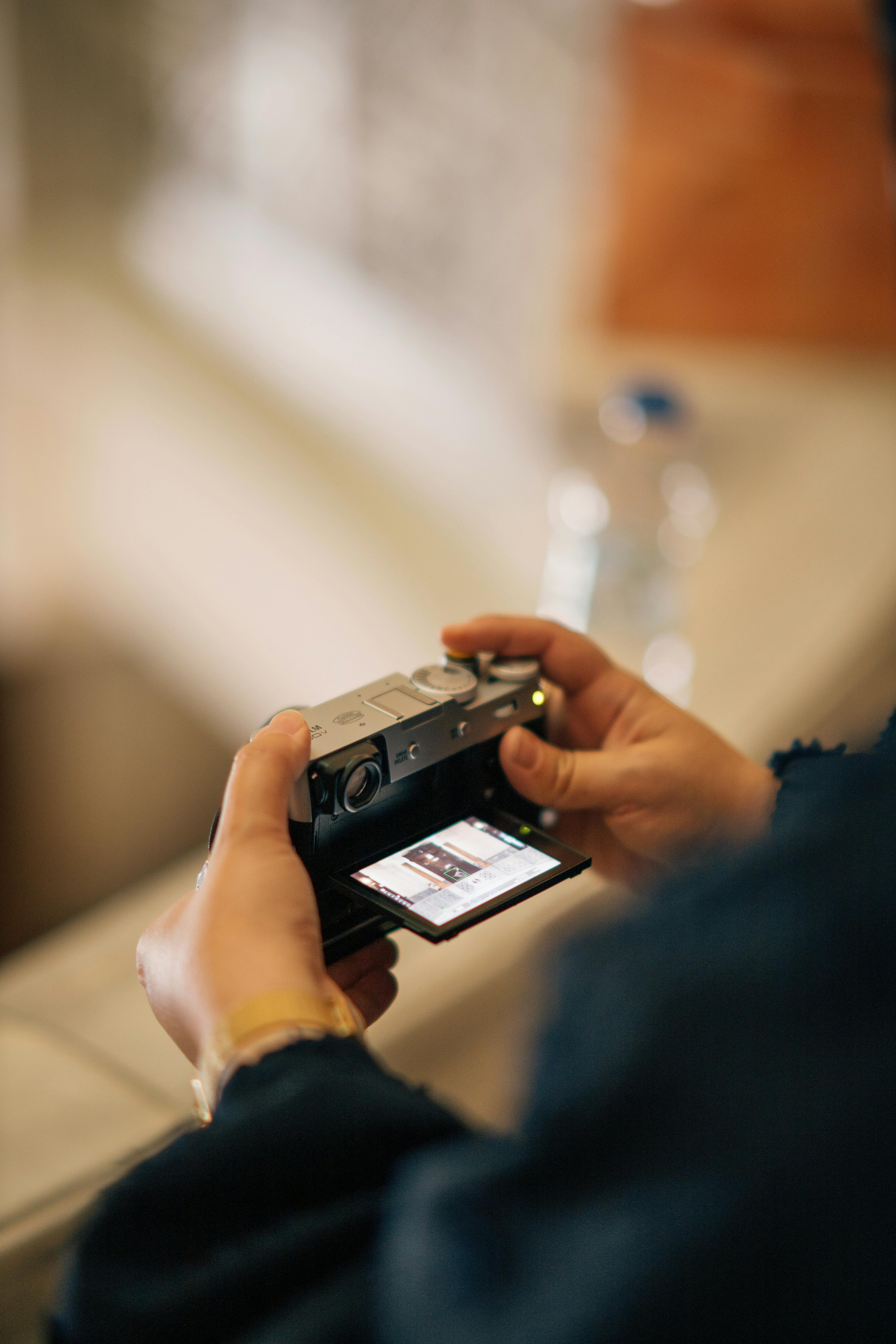 Free Hands holding a camera with a tilting display screen, ready to capture a moment indoors. Stock Photo