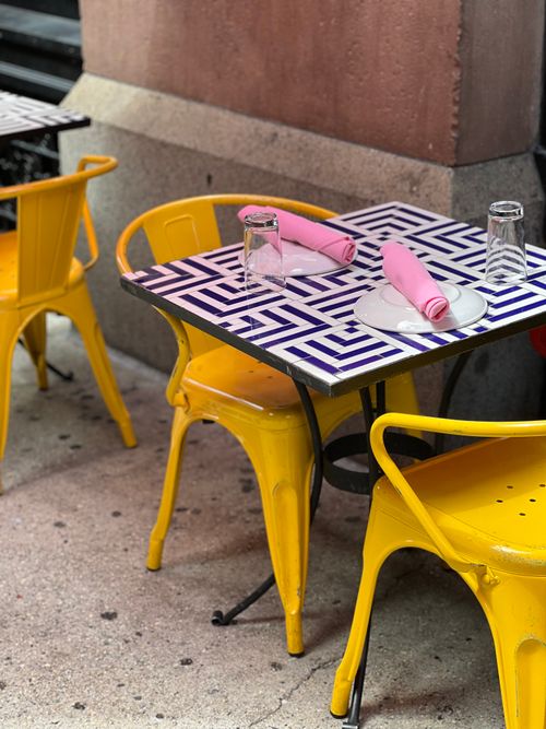 Free Colorful outdoor cafe setting with yellow chairs and geometric table in New York City. Stock Photo