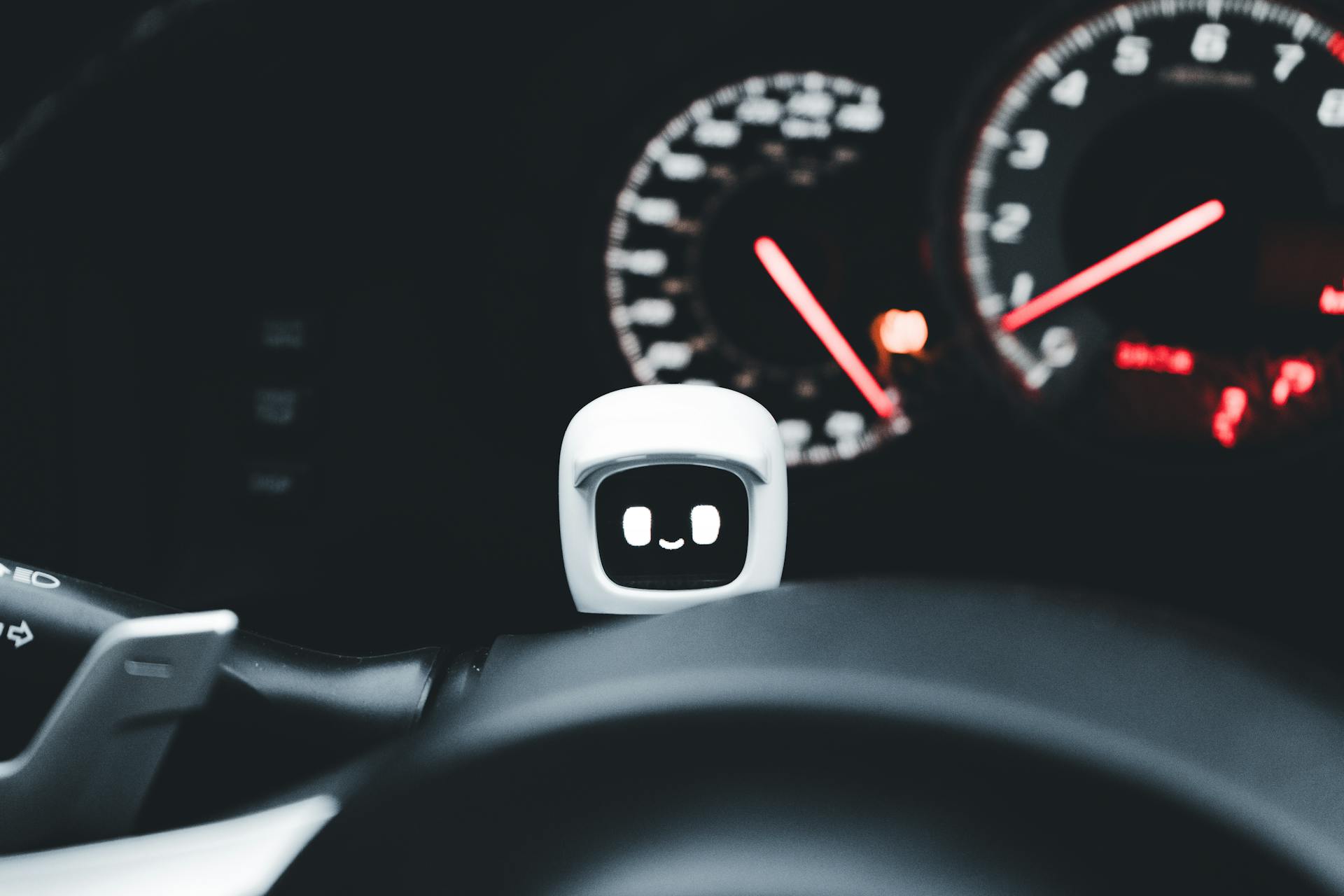 Futuristic smiling robot gadget on a car dashboard symbolizing modern technology and innovation.