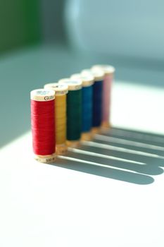 Vibrant close-up of colorful sewing thread spools casting shadows in sunlight.