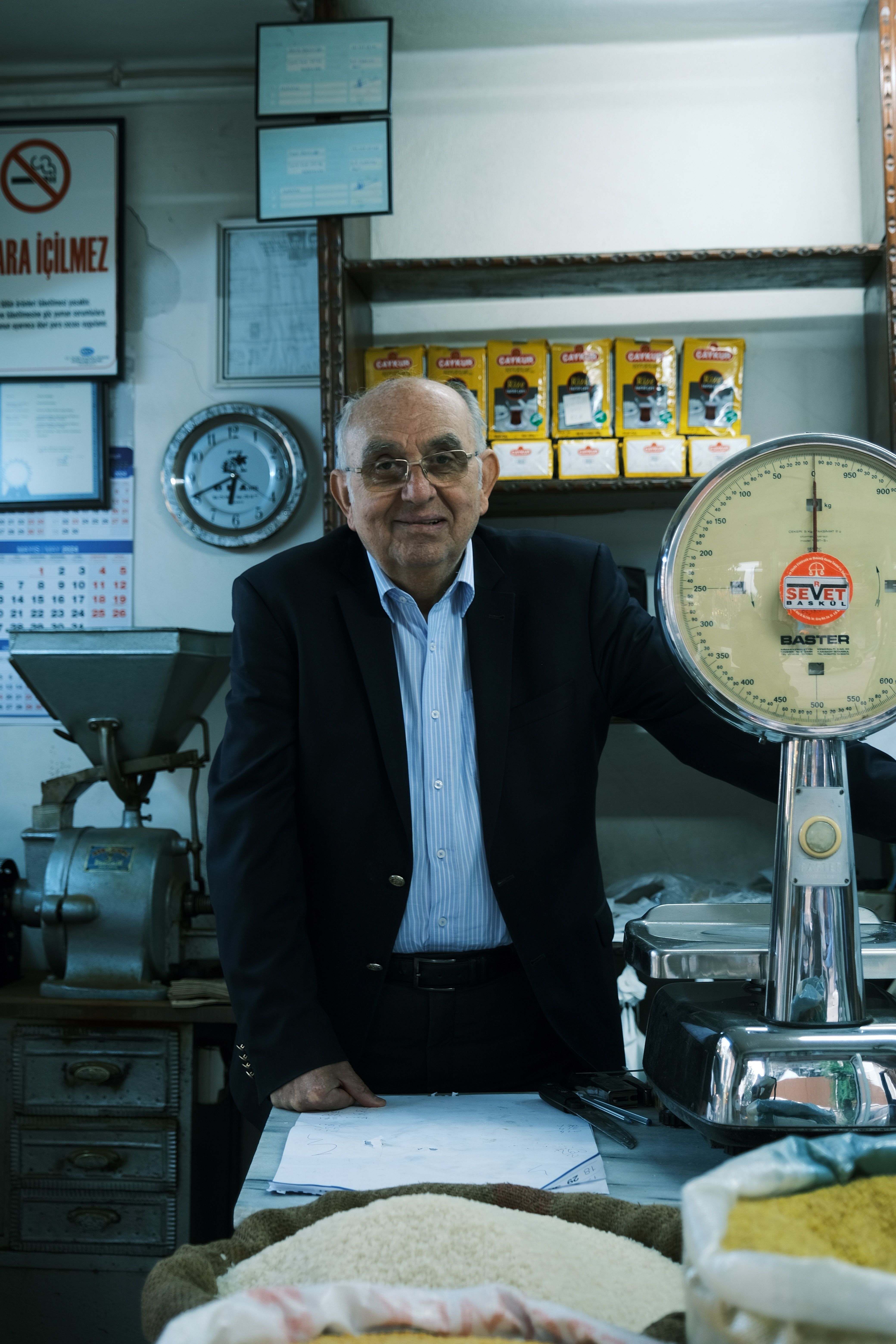Elderly man standing by scale in retail store, showcasing traditional working environment.
