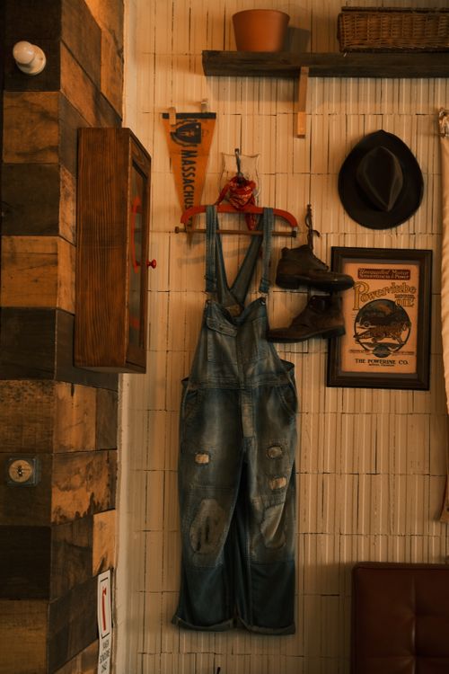 Rustic Overalls Overalls on Hanger with Shoes on Wall · Free Stock Photo