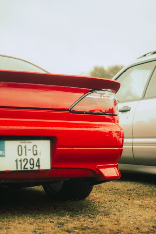 Free Close-up of a red car with spoiler in a misty parking lot, next to a silver vehicle. Stock Photo