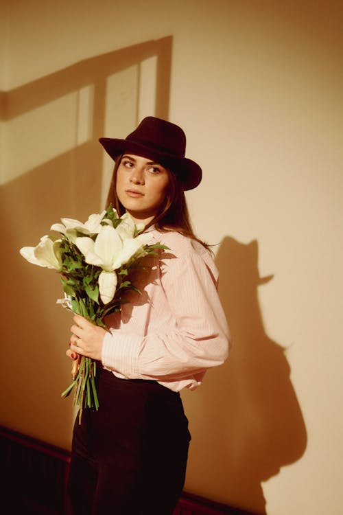 A woman in a hat holding flowers