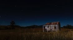 乡村小屋上方的星空映衬着孤独的田园风光