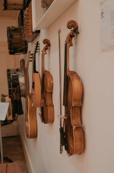 Collection of violins and guitars hanging on a wall in a music studio.