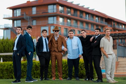 Free Stylish group of young men in suits poses confidently in front of a modern building. Stock Photo