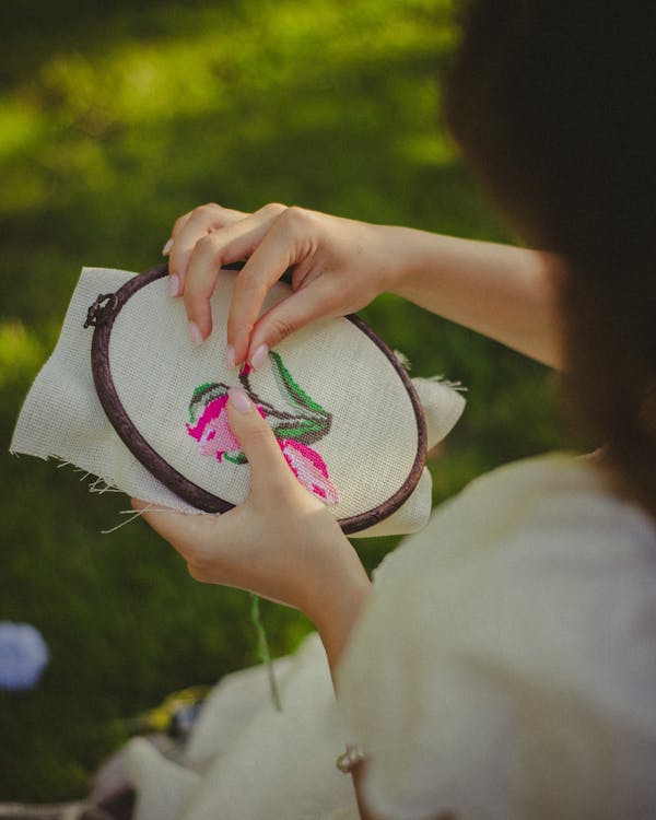 A woman is embroidering a flower on a piece of fabric