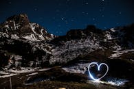在迷人的雪山夜色下，心形光画映衬着星空