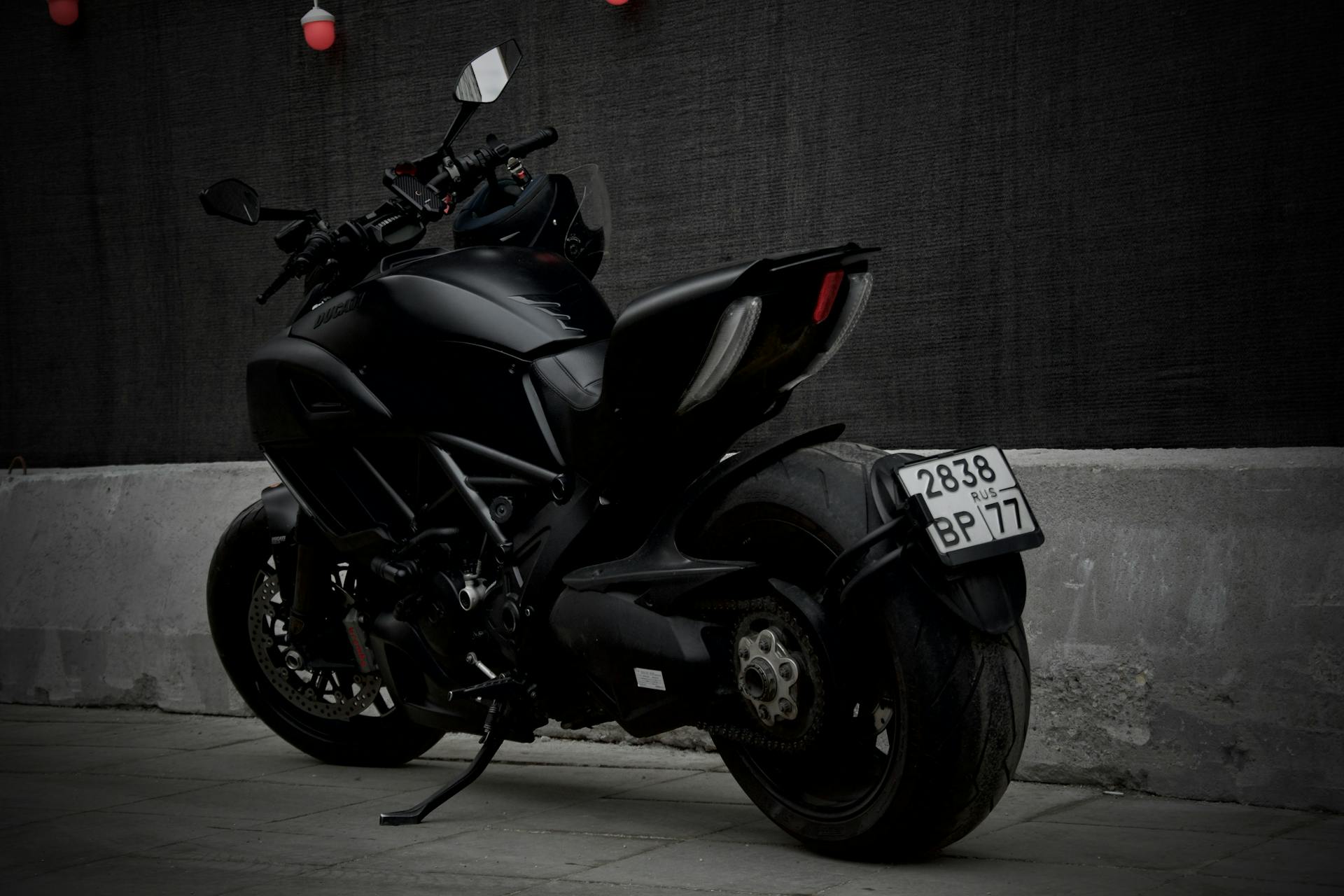 A modern black motorcycle with a visible license plate parked on an urban pavement.