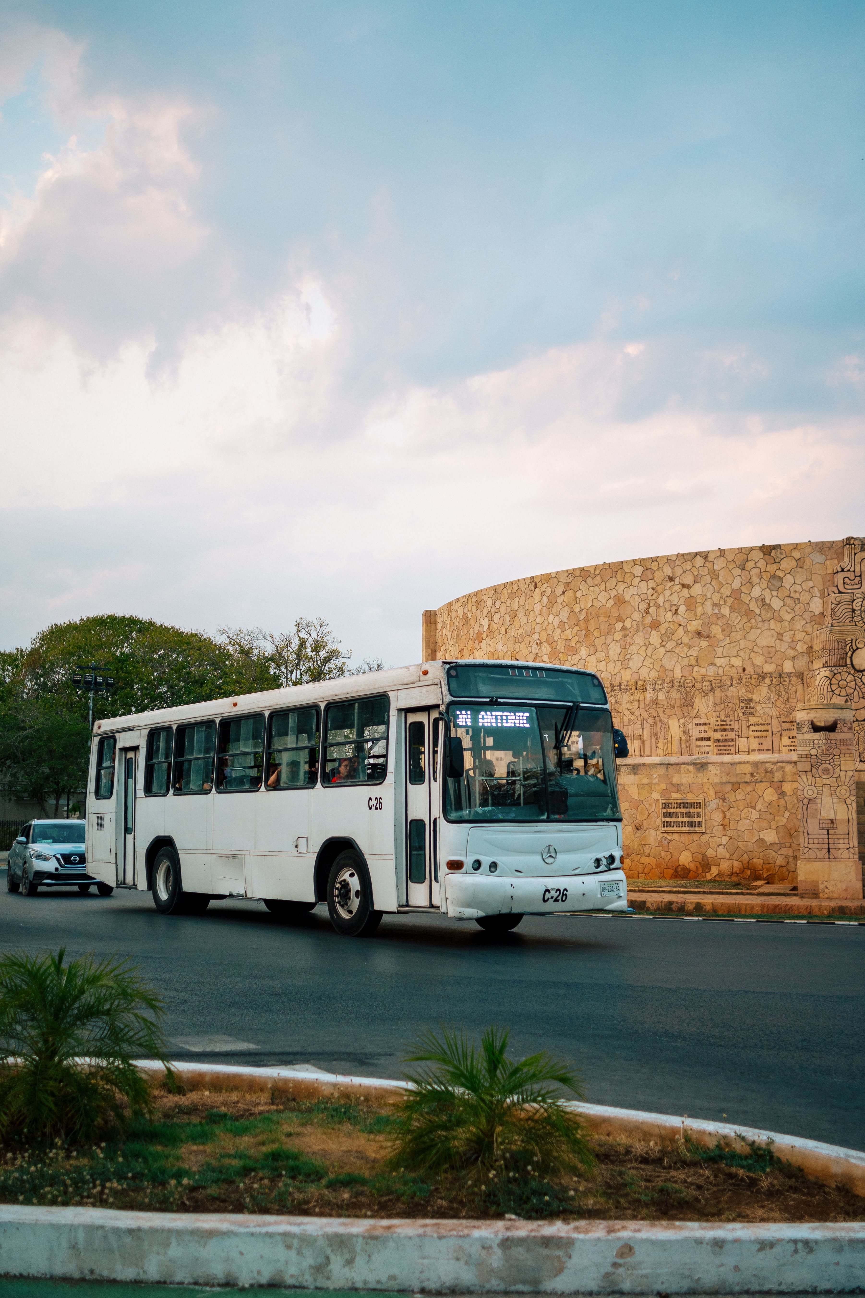 White bus driving down a street in Mérida, Yucatán, at the end of the day