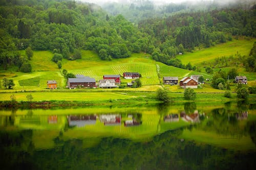 Free White and Brown House on Grass Field Near Body of Water Stock Photo