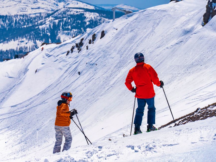 Two skiers navigating a snowy mountain slope in the United States during winter.