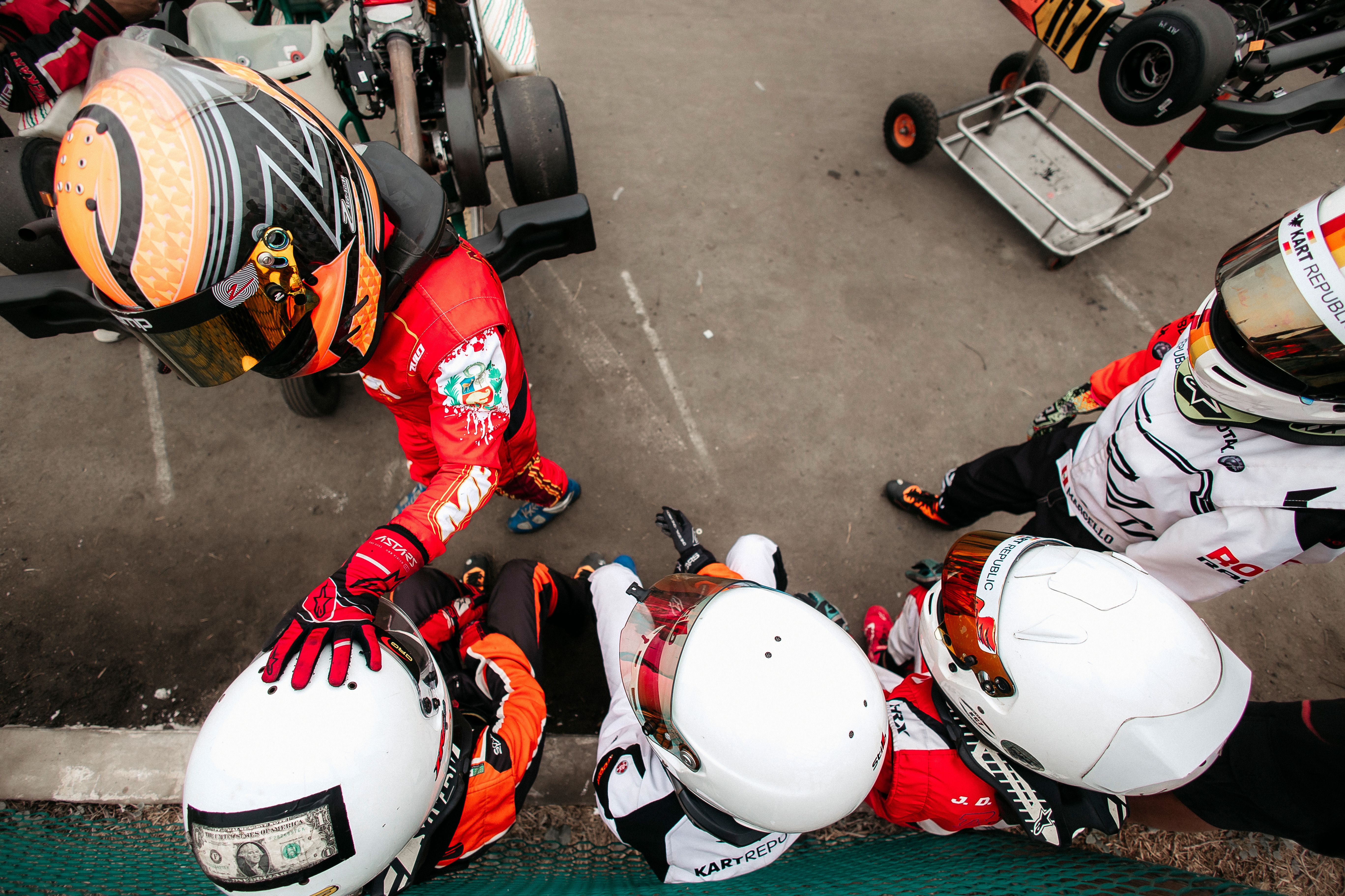 A group of kart racers in racing suits and helmets from above, ready for action.