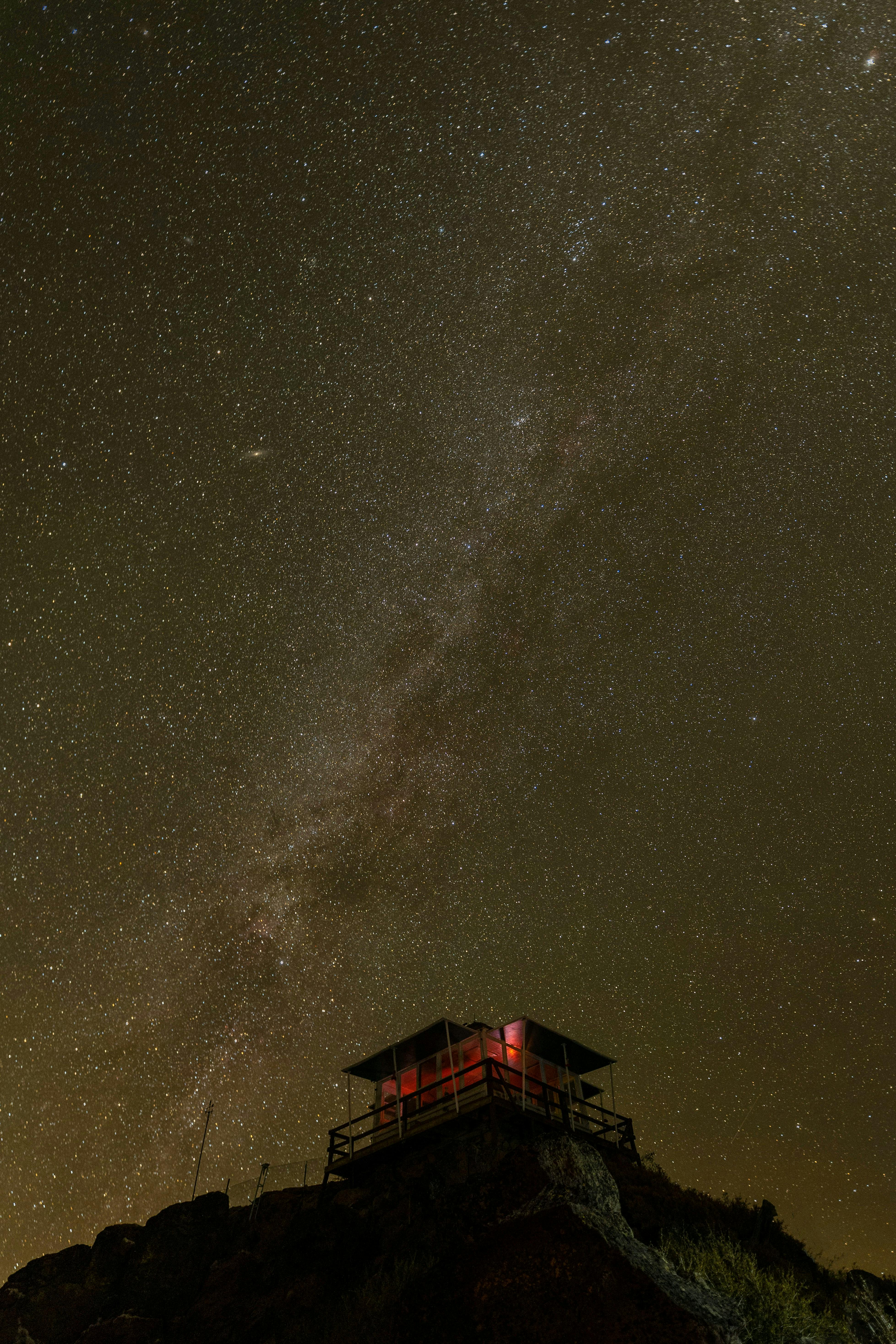 A mesmerizing view of a lone mountain hut under a star-filled night sky.