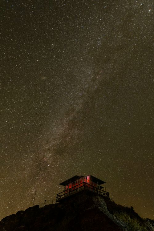 Free A mesmerizing view of a lone mountain hut under a star-filled night sky. Stock Photo